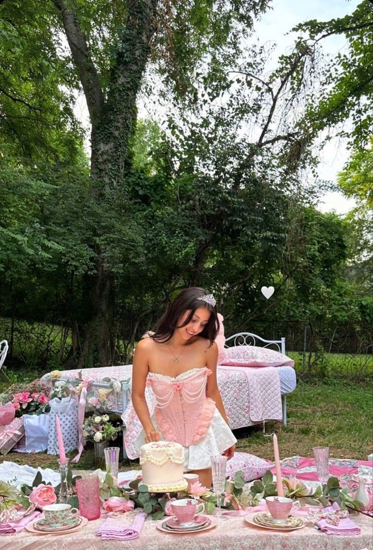 a woman standing in front of a table covered with pink and white plates, cups and cake