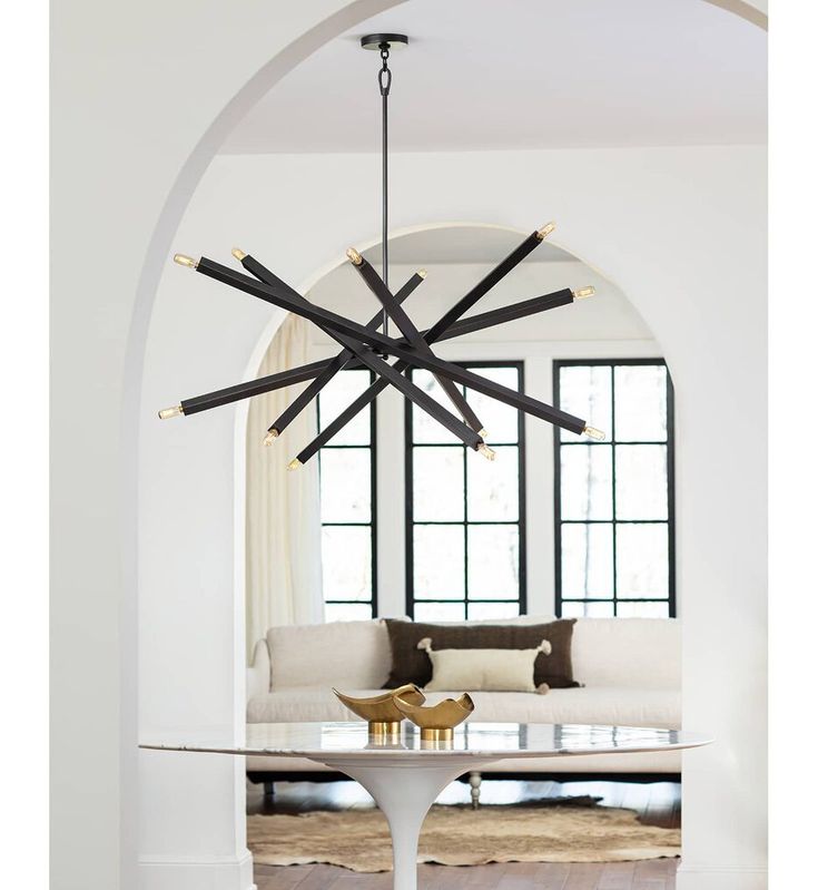 a living room with a couch, table and chandelier hanging from the ceiling