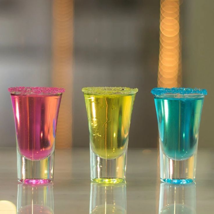 three colorful shot glasses sitting on top of a table