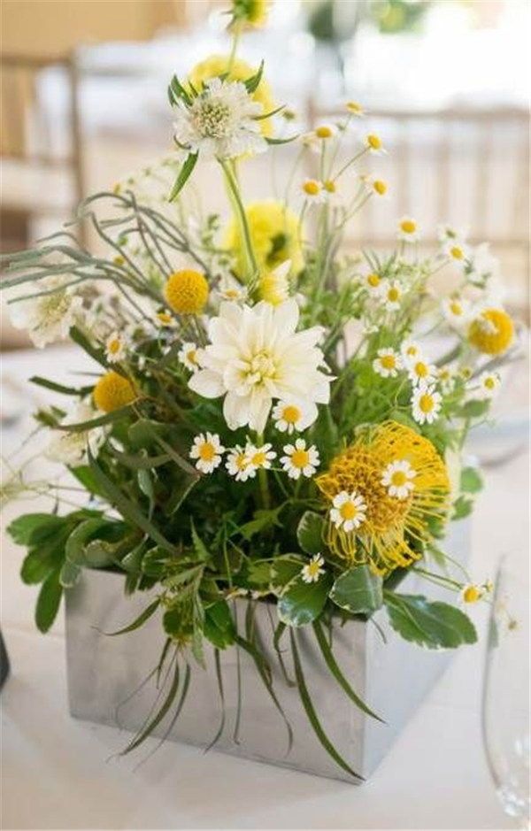 a vase filled with yellow and white flowers on top of a table