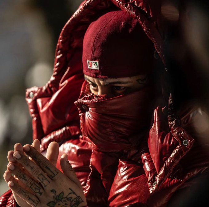 a person wearing a red outfit and covering her face with a scarf around their head