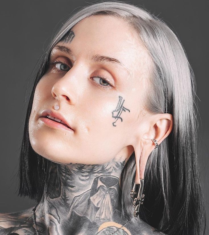 a woman with tattoos and piercings on her neck