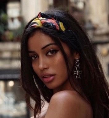 a woman with long hair wearing a headband and earrings on her head is looking at the camera