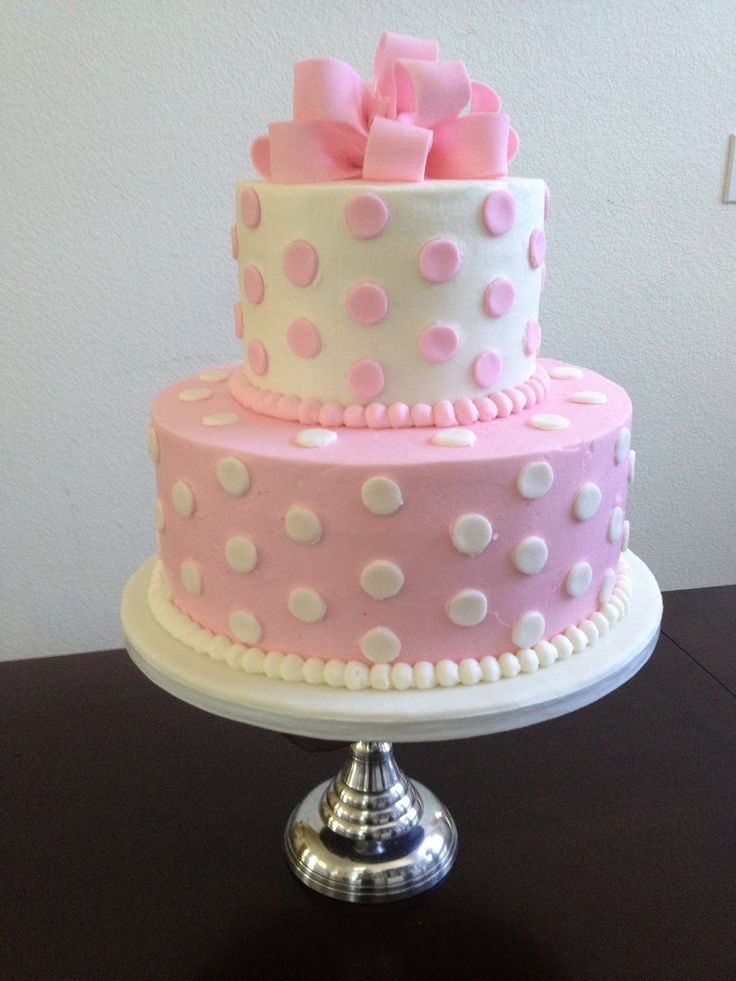 a three tiered cake with pink and white polka dots on the top, sitting on a table