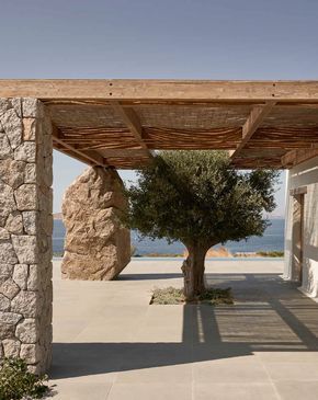 an outdoor area with stone walls and a tree in the foreground, overlooking the ocean