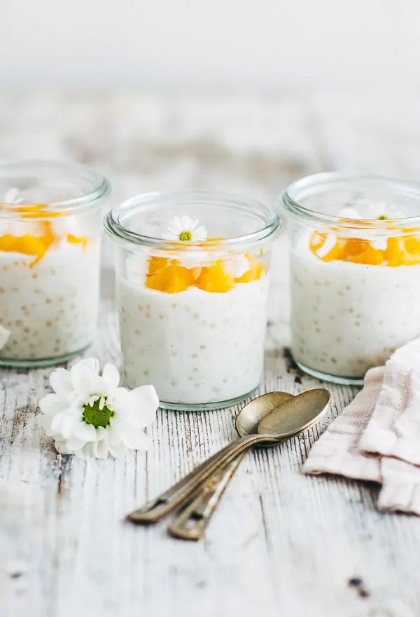 three small jars filled with food sitting on top of a table next to spoons