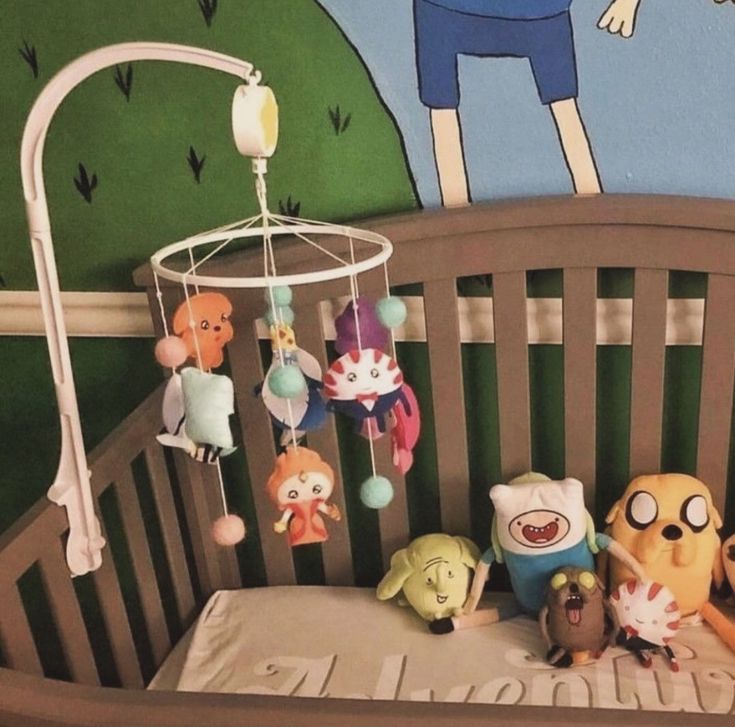 a baby crib with stuffed animals in it next to a cartoon wallpaper mural