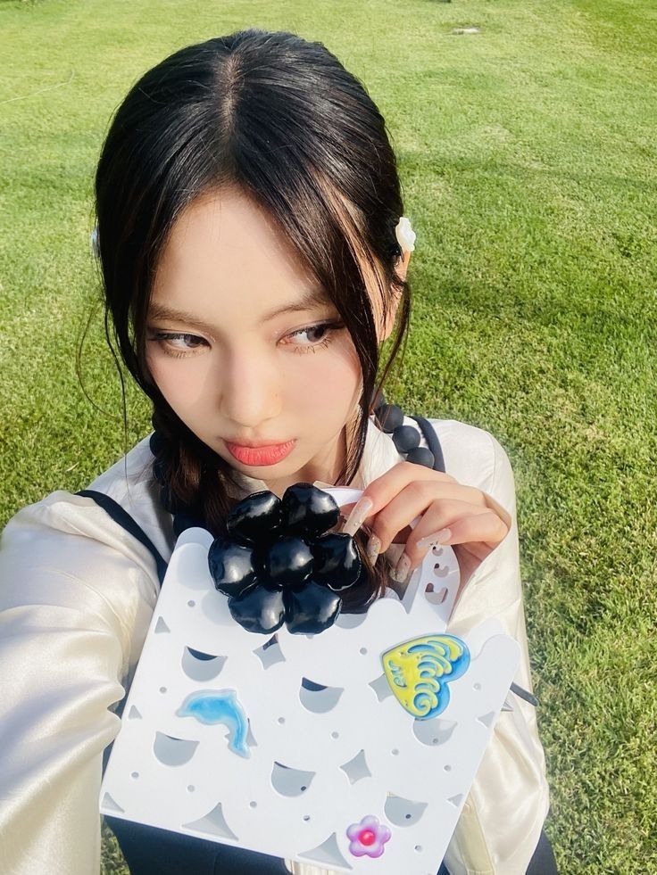 a young woman holding up a box with grapes on it in front of her face