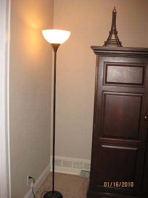 a floor lamp next to a wooden door in a room with the word before written on it