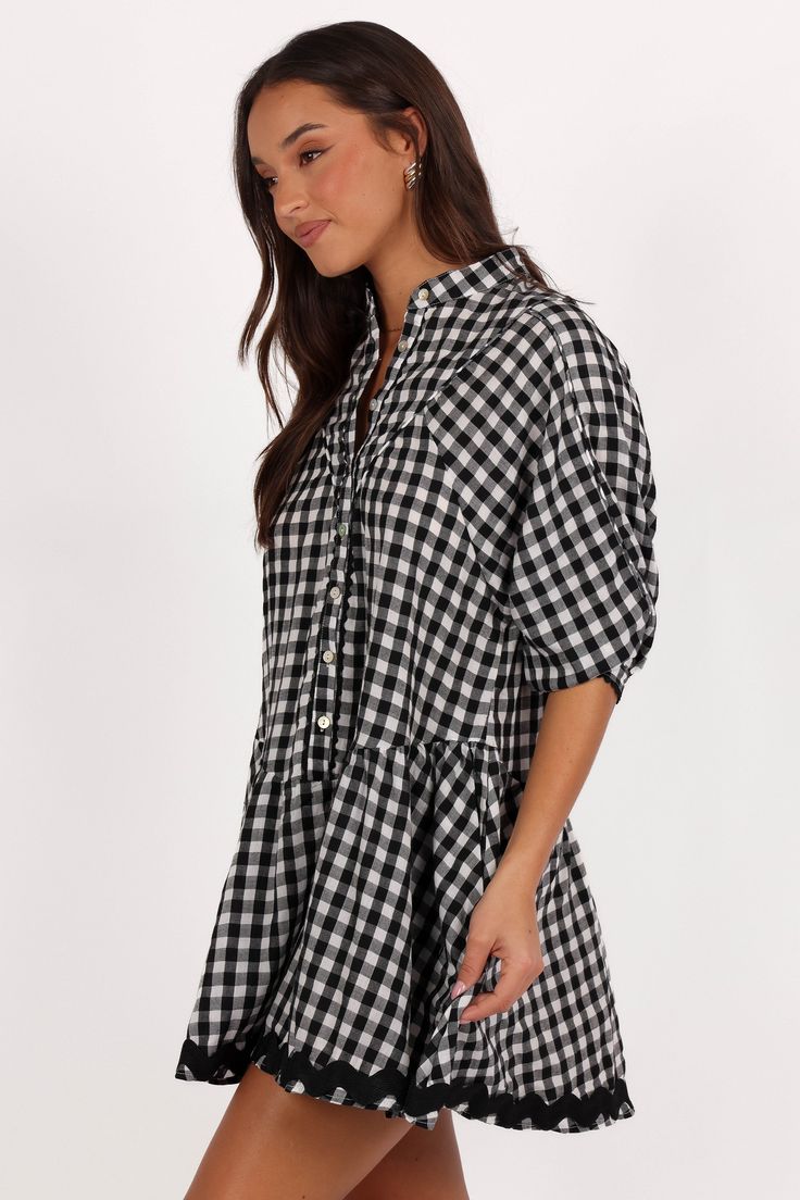 DETAILS  Designed for the fashion-forward woman who appreciates both comfort and style, this mini dress is a versatile addition to your wardrobe. Whether you're pairing it with sandals for a casual day out or dressing it up with heels for a chic evening look.    mini length  high round neckline  short sleeves  functional button down  ric rac trim on hem  gingham print  unlined  material - 100% cotton    SIZING     model is 5' 7" and wears a Size S    model stats: bust - 33", waist - 26", hips - Casual Plaid Dress For Spring Picnic, Casual Cotton Plaid Dress For Vacation, Black Plaid Cotton Mini Dress, Black Cotton Plaid Mini Dress, Casual Gingham Dress For Day Out, Casual Gingham Plaid Dress For Spring, Spring Black Plaid Mini Dress, Black Plaid Mini Dress For Spring, Spring Black Plaid Mini Length Dress