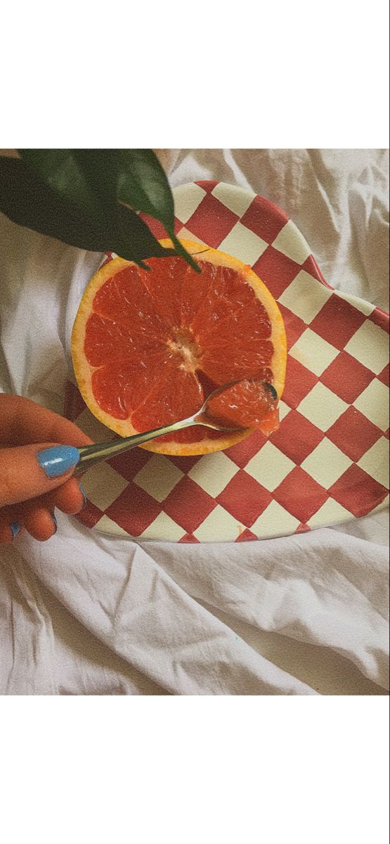 a person cutting up an orange on a checkered plate with a pair of scissors