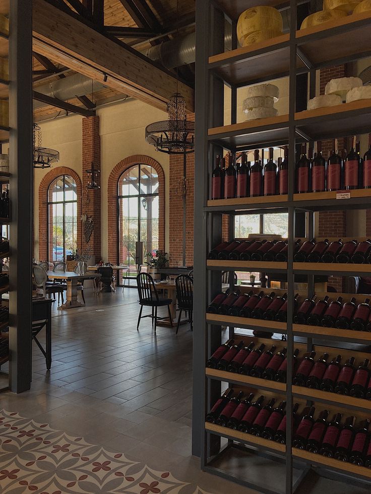 a large room with many shelves filled with bottles and wine glasses on the wall, along with tables and chairs