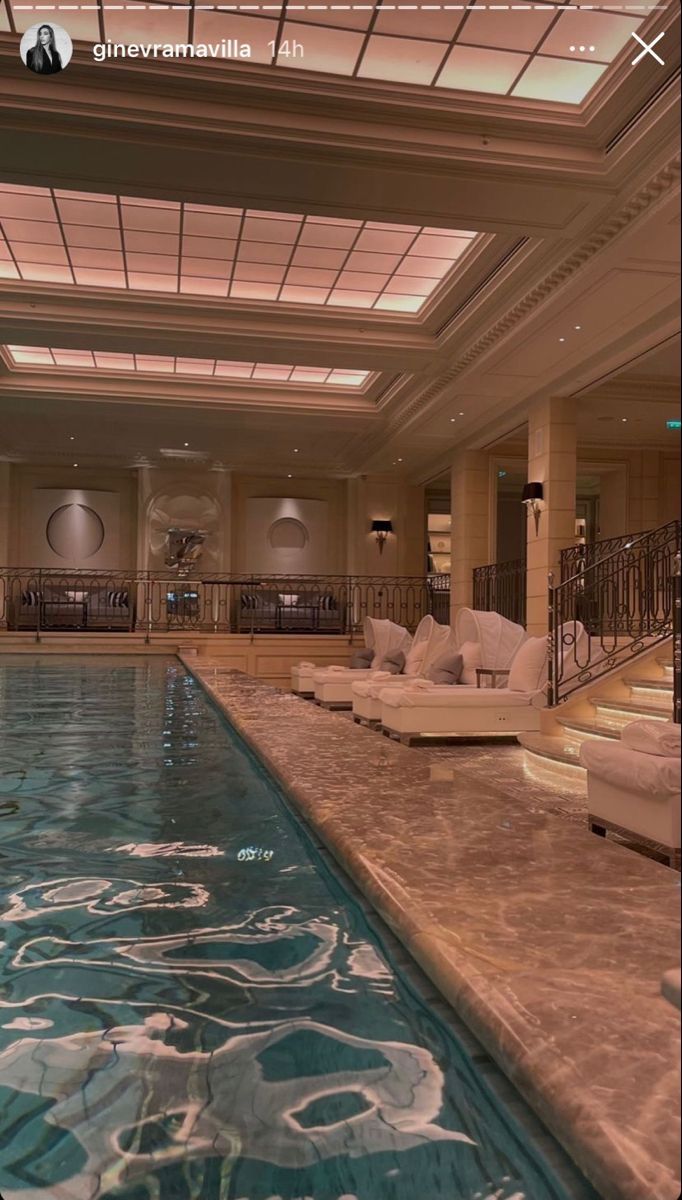 a large indoor swimming pool with lounge chairs and stairs leading to the upper floor area