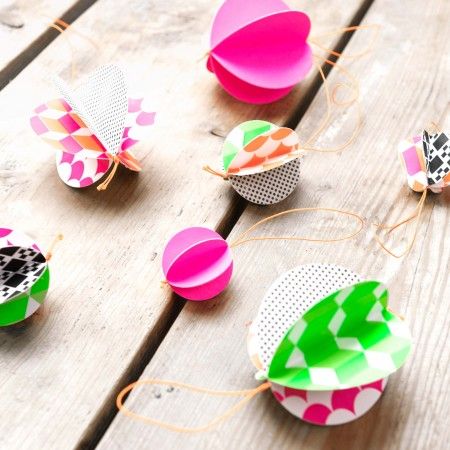 colorful paper flowers are tied to string on a wooden table