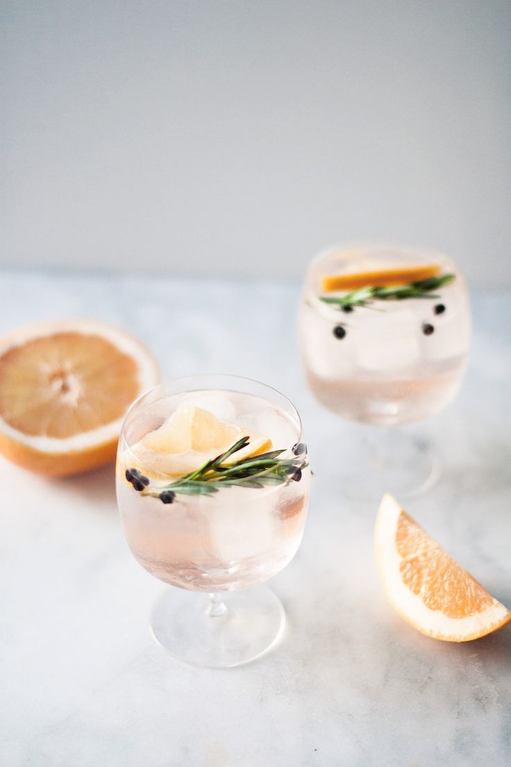 two glasses filled with lemonade and rosemary garnish on top of a marble table