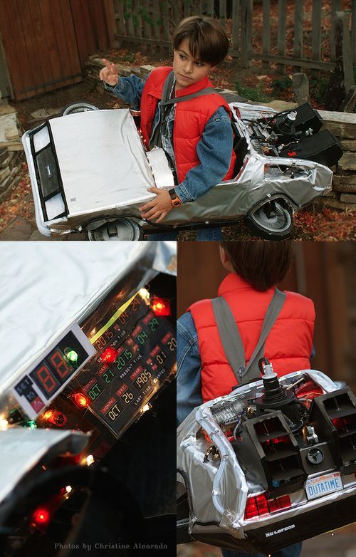 a boy sitting on the ground next to a toy car and an electronic device that is attached to it