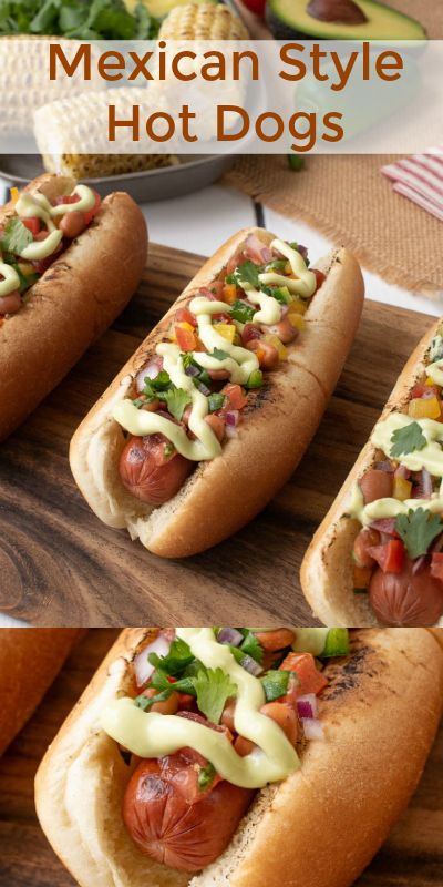 four hot dogs with toppings sitting on a cutting board