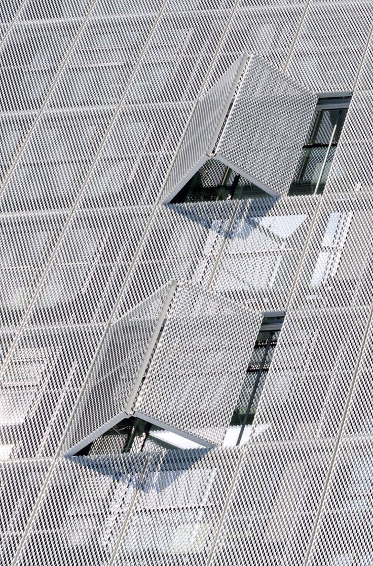 two windows on the side of a building that has mesh coverings over it and are open