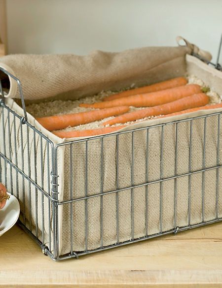 some carrots are sitting in a wire basket on a table next to a plate