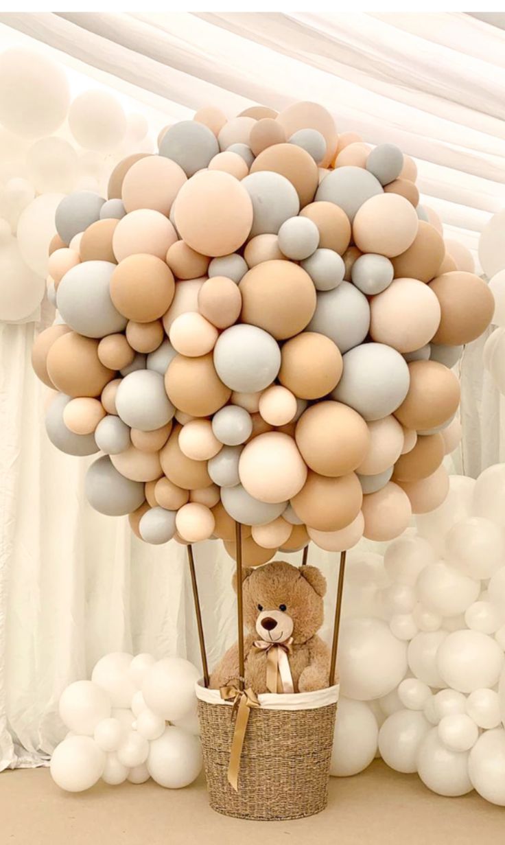 a teddy bear in a basket with balloons