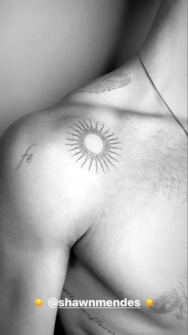 a black and white photo of a man's chest with the sun tattoo on it