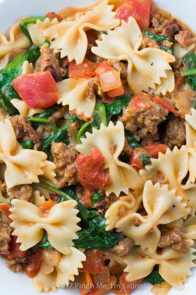 pasta with meat and spinach in a white bowl