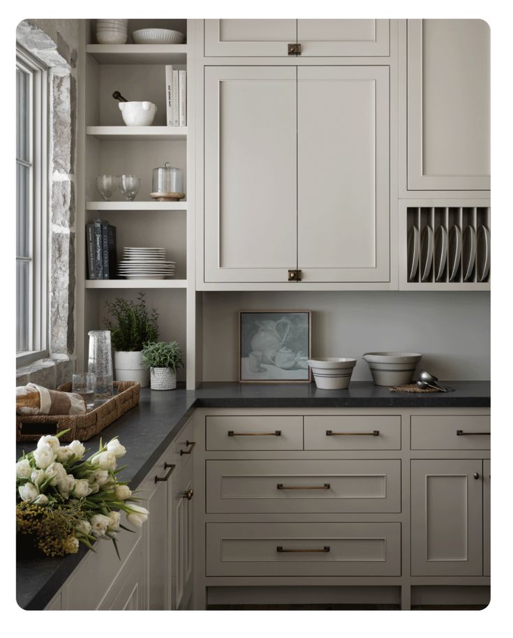 a kitchen filled with lots of white cupboards and counter top space next to a window