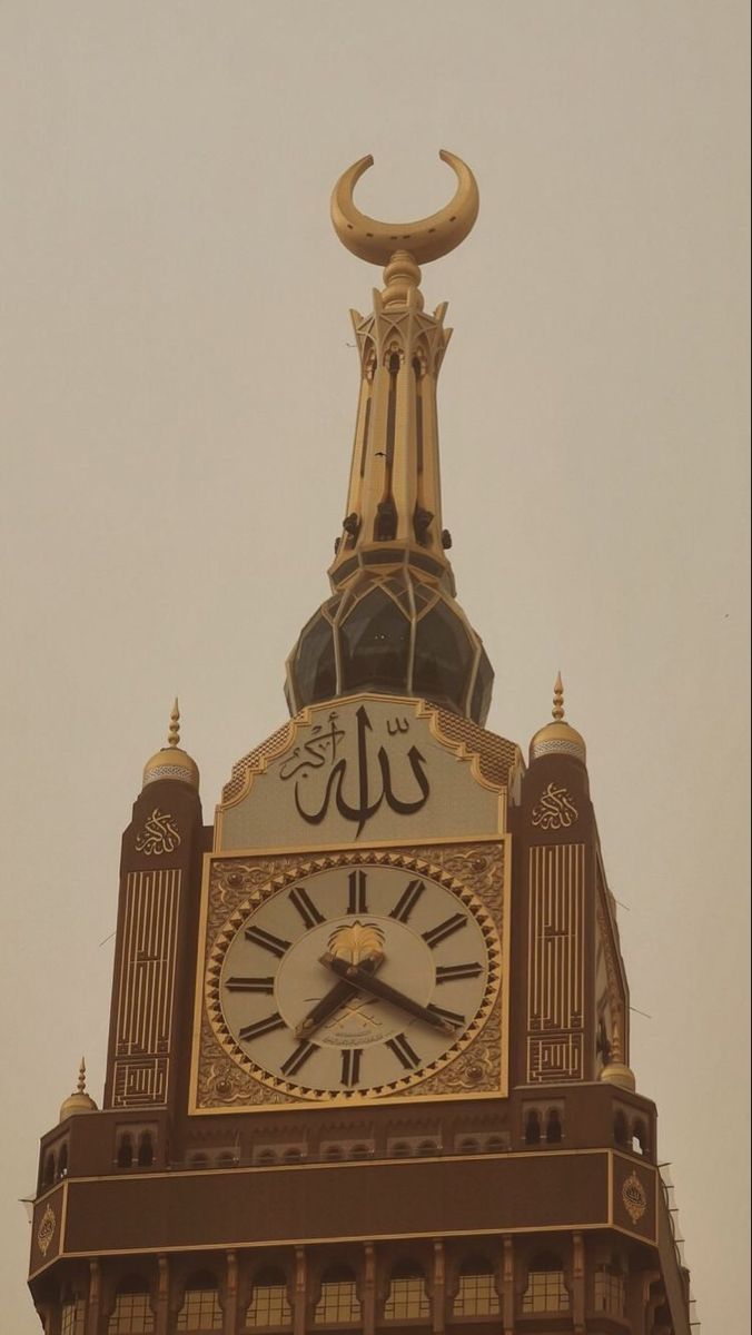 a clock tower with arabic writing on it's sides and a crescent above the clock