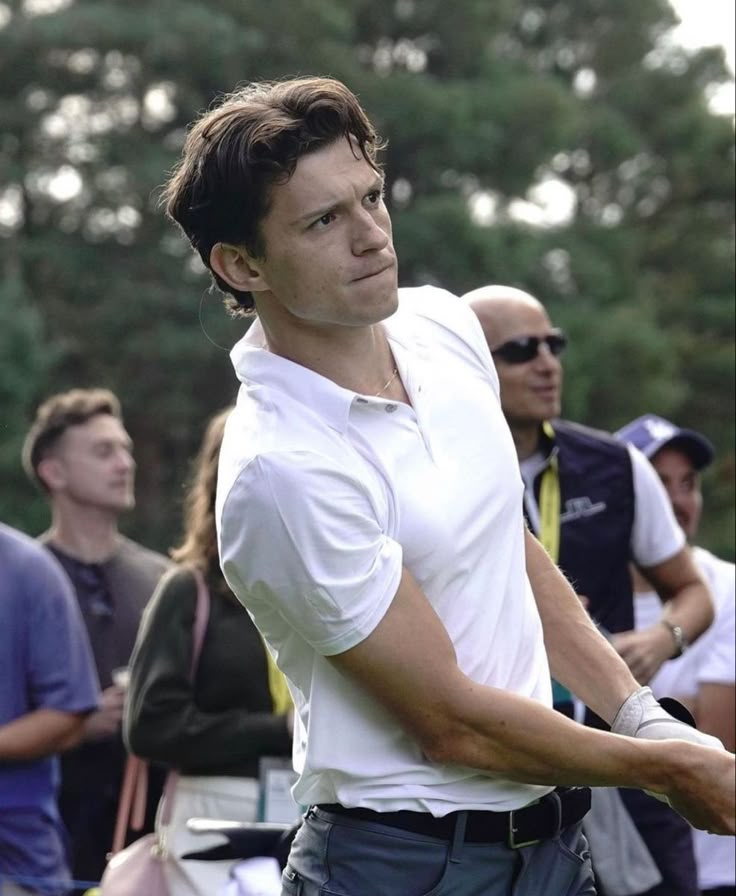 a man holding a tennis racquet on top of a green grass covered field