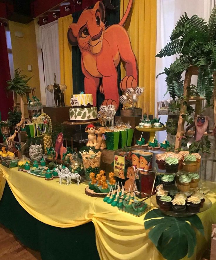 the lion king dessert table is set up with cupcakes, cake and candy