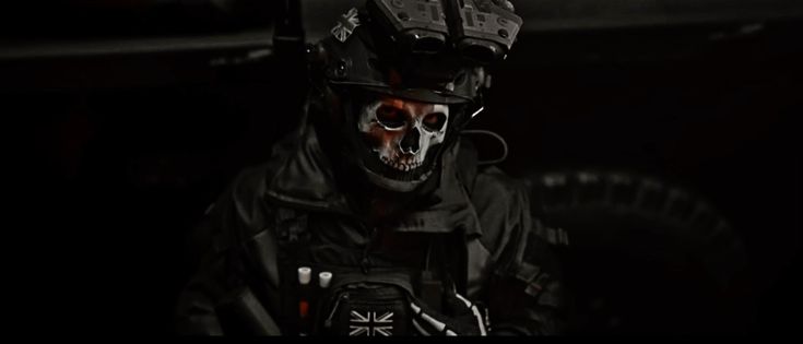 a man wearing a motorcycle helmet and painted skull on it's face in the dark