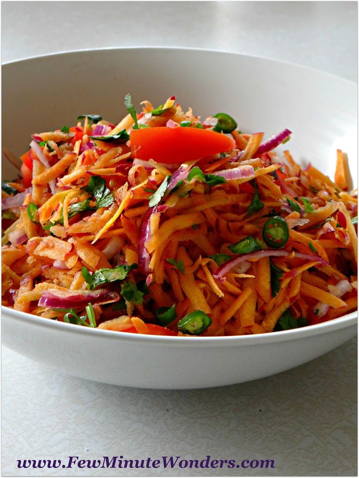 a white bowl filled with shredded carrots and red onions on top of a table