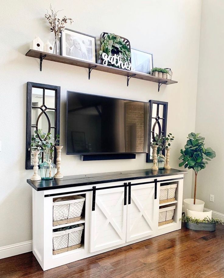 a living room with white furniture and a flat screen tv on top of a entertainment center