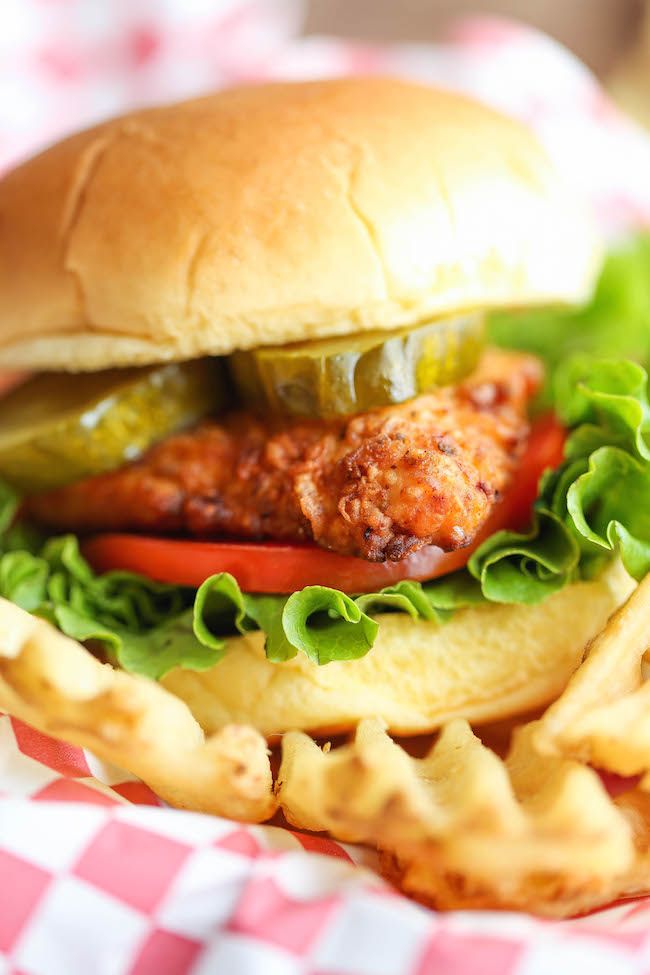 a chicken sandwich with lettuce, tomato and pickles on a bun in a basket