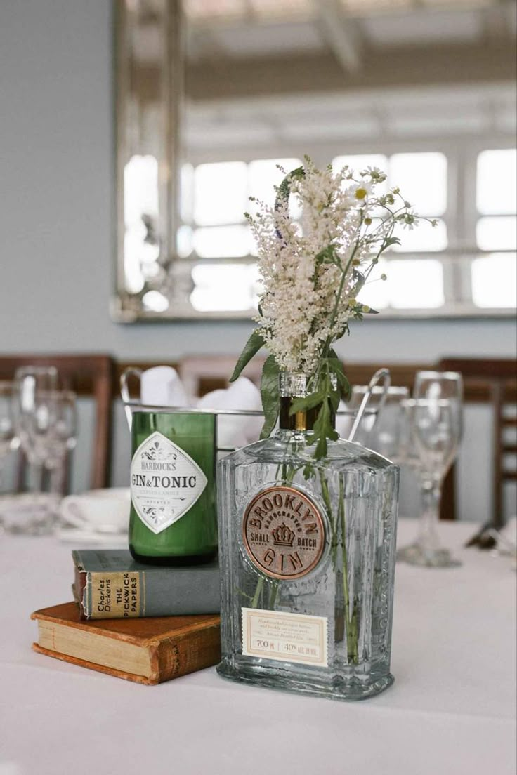 a vase with flowers sitting on top of a table next to books and wine glasses