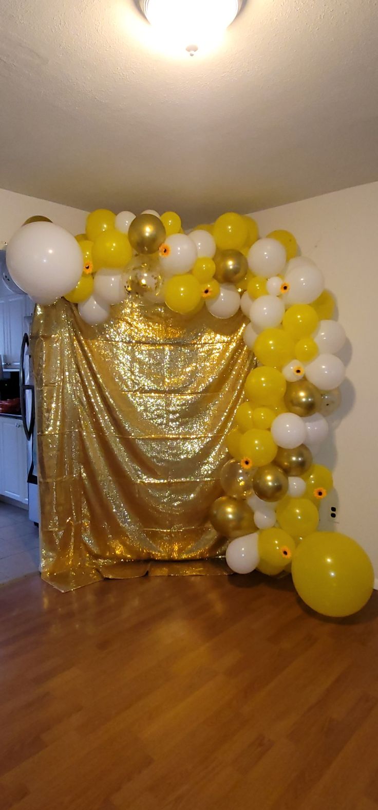 balloons and streamers are on the floor in front of a gold draped curtain,