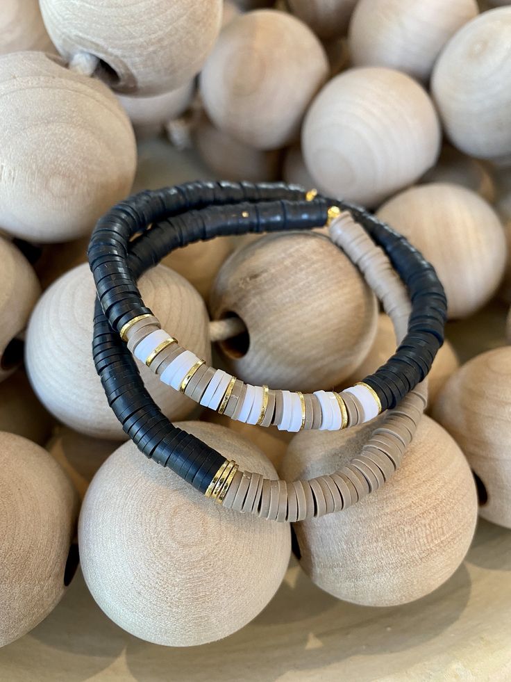 "This listing is for a set of TWO tan, black and white bracelets. The heishi beads are 6mm. My hand-beaded bracelets are made with stretch elastic which makes it comfortable and easy to wear. They are made to fit an average wrist size of 6.5\"-7\". Take a look around my shop for additional colors to add to your stack! I've included pictures to give you an idea of bracelets to add to your set." Clay Bead Bracelet Ideas Black And White, Black Heishi Beads Stretch Bracelet As Gift, Neutral Clay Bead Bracelets, Adjustable Brown Heishi Beads Bracelets, Adjustable Black Heishi Beads Stretch Bracelet, Black Clay Bead Bracelet, Black And Gold Clay Bead Bracelet, Brown Heishi Beaded Bracelets Gift, Brown Beaded Heishi Bracelets