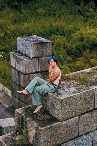 a woman sitting on top of a stone wall