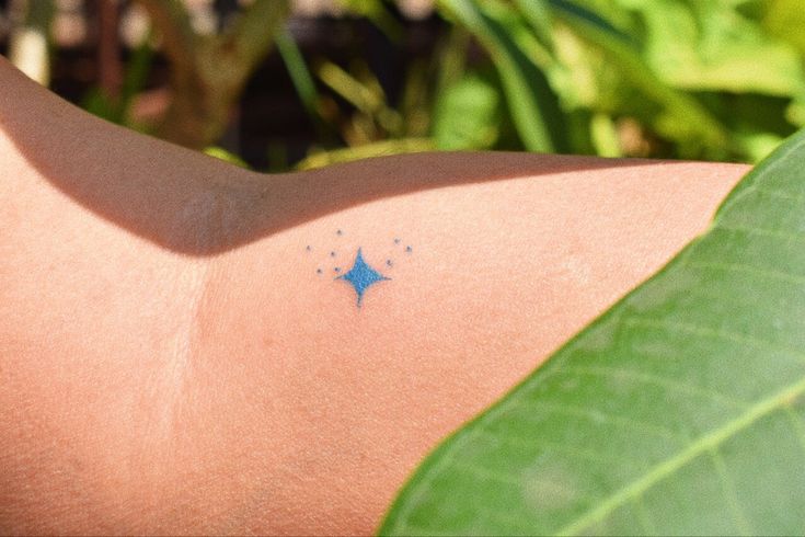 a tattoo on the back of a person's shoulder with blue stars painted on it