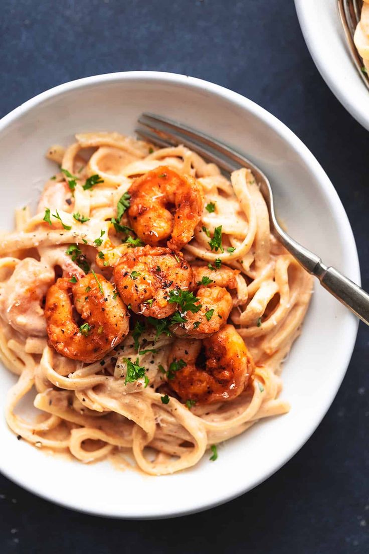 pasta with shrimp and parmesan sauce in a white bowl on a blue table