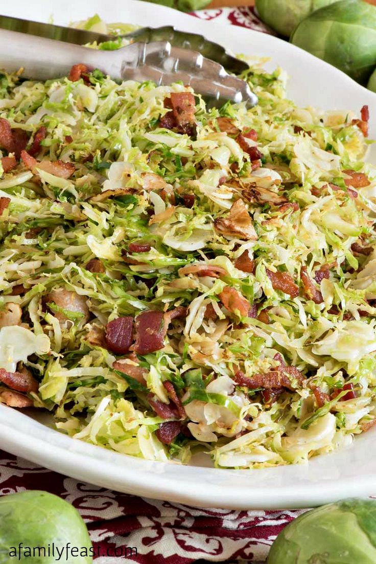 a white bowl filled with shaved brussels sprouts and bacon on top of a table