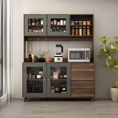 a kitchen area with a microwave, cabinets and potted plant