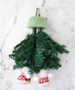 a green christmas tree with red and white shoes hanging from it