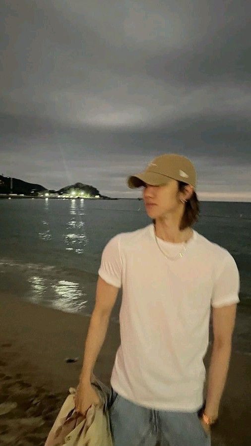 a man standing on top of a beach next to the ocean