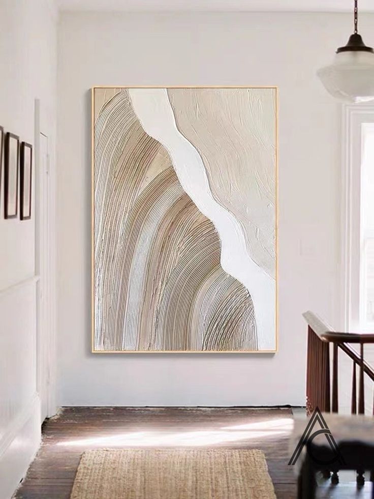 an abstract painting hangs on the wall above a wooden table in a white room with dark wood floors