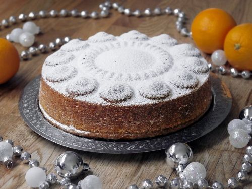 a cake is sitting on a plate with silver balls around it and some oranges in the background