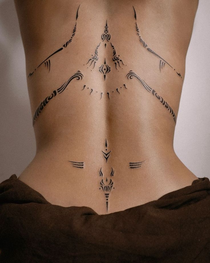 the back of a woman's lower body with arrows drawn on her stomach and an arrow tattoo