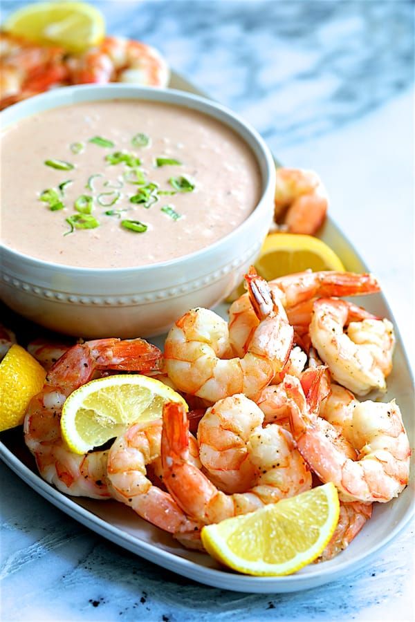 a plate with shrimp, lemon wedges and dipping sauce