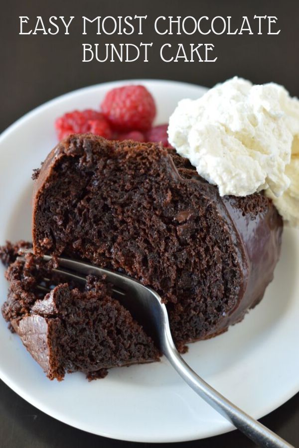 devil's food cake on a white plate with whipped cream and raspberries