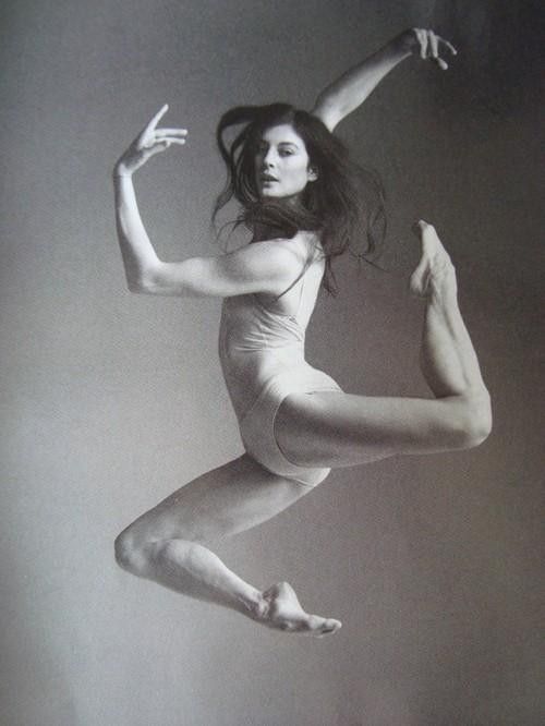 a woman is jumping in the air with her legs spread out and one hand on her hip